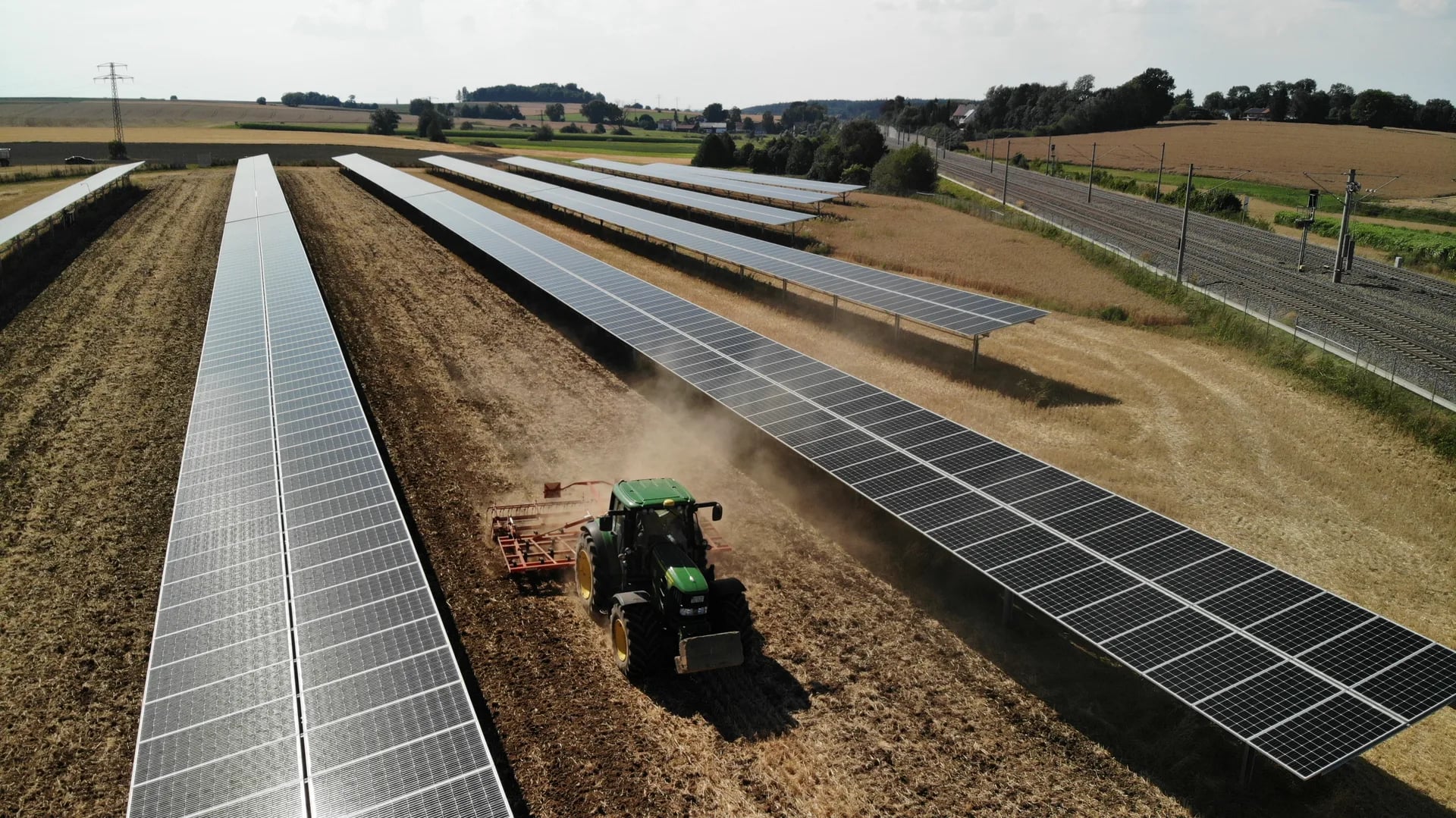 Drohnenaufnahme einer Agri-PV Anlage mit Traktor bei der Feldarbeit
